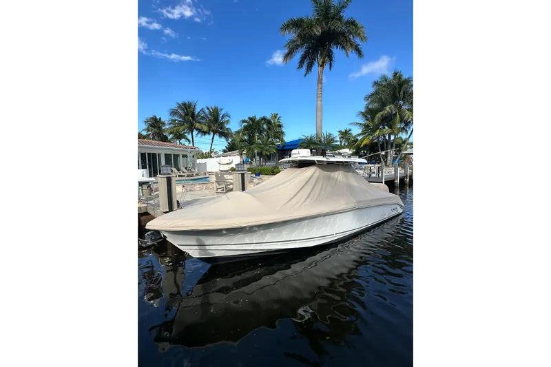  Yacht Photos Pics 2020 Boston Whaler 330 Outrage boat covered at dock, surrounded by palm trees.