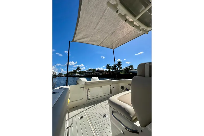  Yacht Photos Pics 2020 Boston Whaler 330 Outrage boat interior with canopy, overlooking a scenic waterfront.