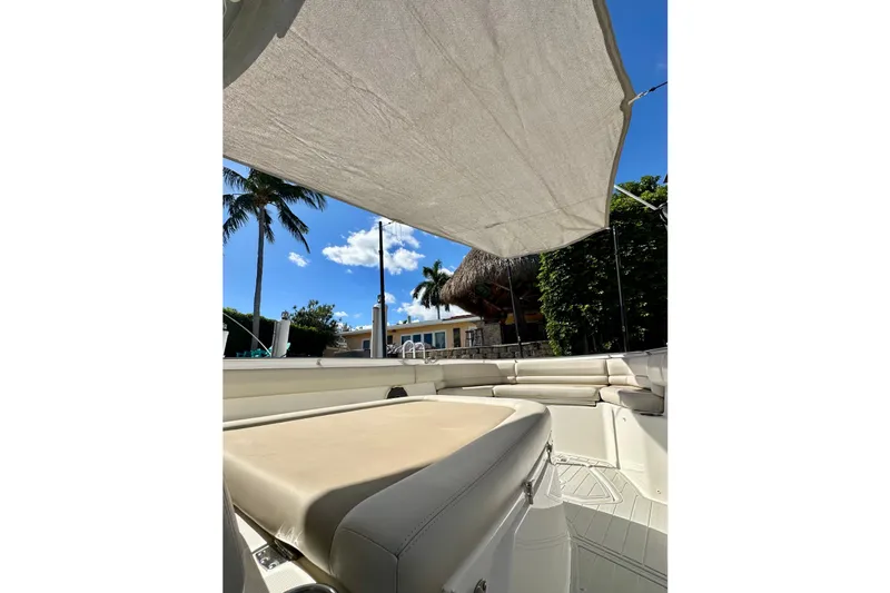  Yacht Photos Pics 2020 Boston Whaler 330 Outrage boat interior with sunshade, palm trees, and clear sky.
