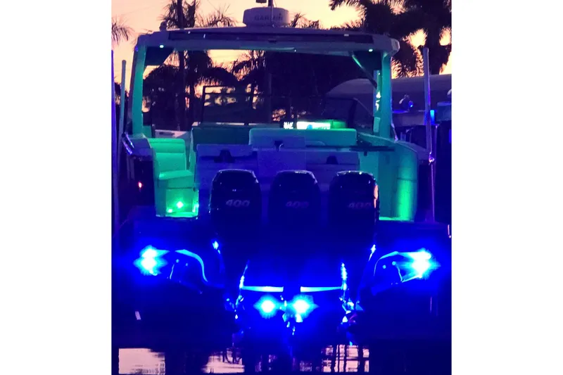Happy Our II Yacht Photos Pics 2022 Aviara AV40 OB boat illuminated with vibrant blue and green lights at sunset.
