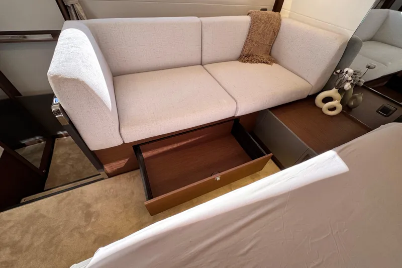 Yacht Photos Pics 2024 Prestige M48 interior with beige sofa, open storage drawer, and decorative items.