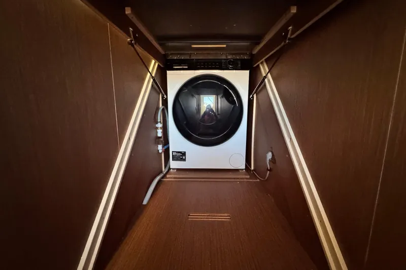  Yacht Photos Pics 2024 Prestige M48 interior with a modern washing machine in a wooden compartment.