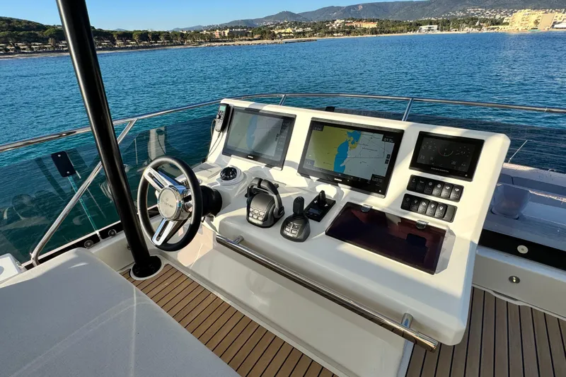  Yacht Photos Pics 2024 Prestige M48 yacht helm with navigation screens and controls, overlooking serene blue waters.