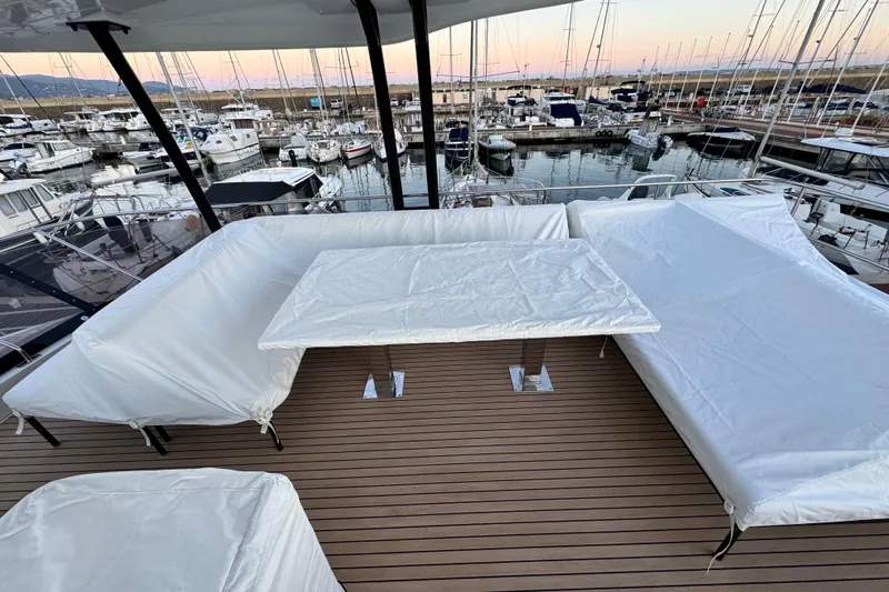  Yacht Photos Pics 2024 Prestige M48 yacht deck with covered seating and table, docked at marina.