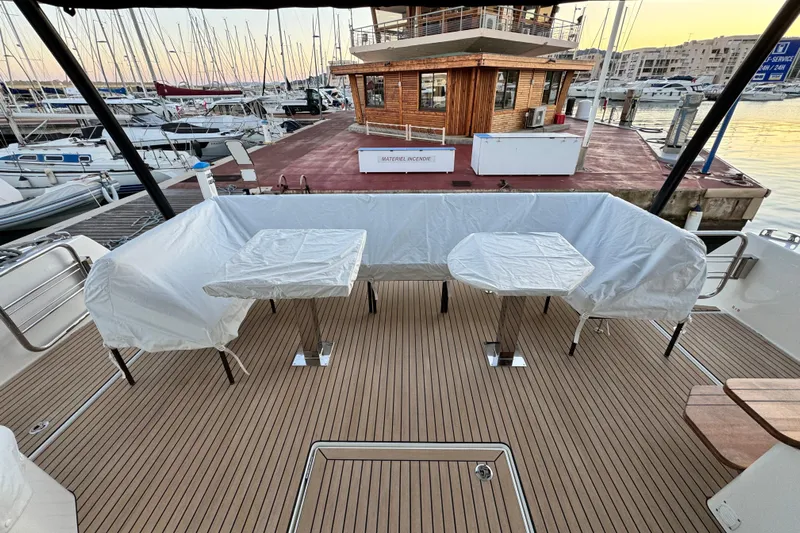  Yacht Photos Pics 2024 Prestige M48 yacht deck with covered seating and tables at marina.