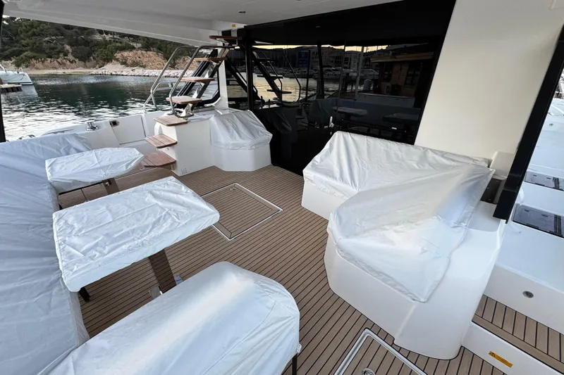  Yacht Photos Pics Luxury 2024 Prestige M48 yacht deck with covered seating and tables, docked by serene waters.