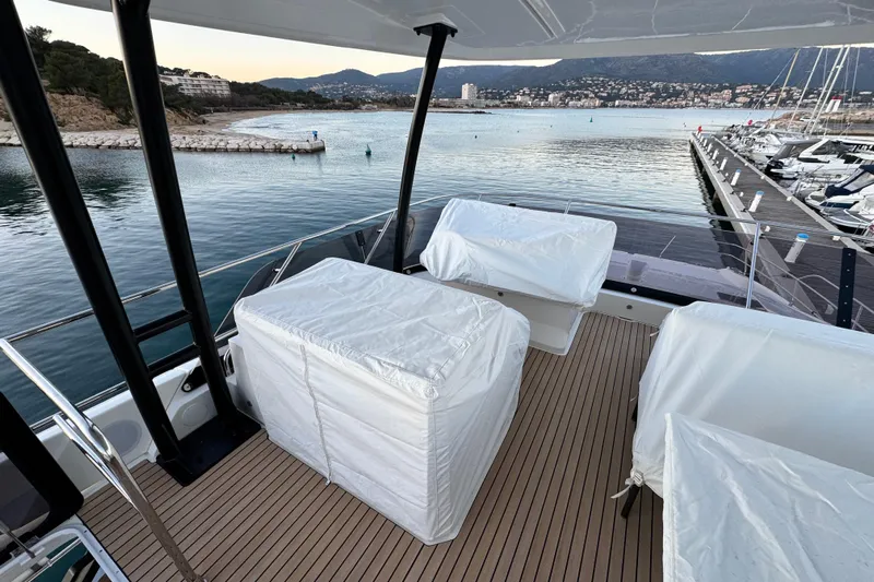  Yacht Photos Pics Luxurious 2024 Prestige M48 yacht deck with covered seating, overlooking serene marina and coastline.