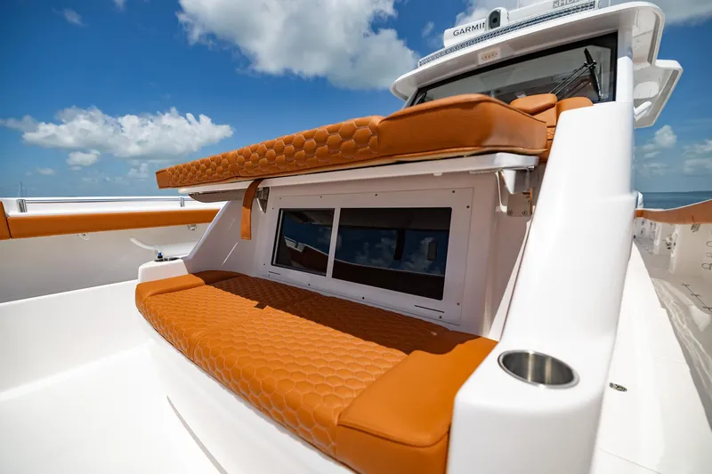  Yacht Photos Pics 2023 Invincible 46 Pilothouse with orange seating and sleek design under blue sky.
