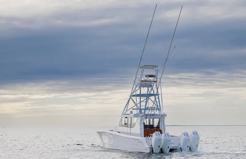  Yacht Photos Pics 2023 Invincible 46 Pilothouse boat on calm sea under cloudy sky.