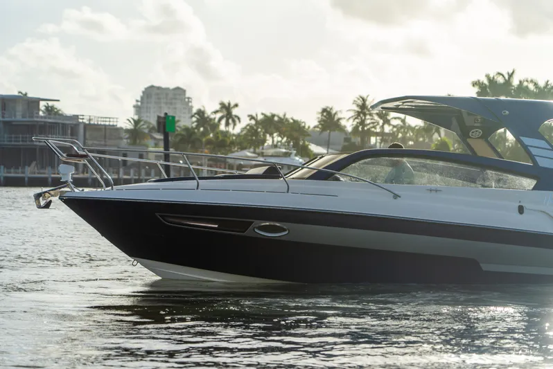  Yacht Photos Pics 2024 Hanover 305 boat cruising on a sunny waterfront with palm trees in the background.