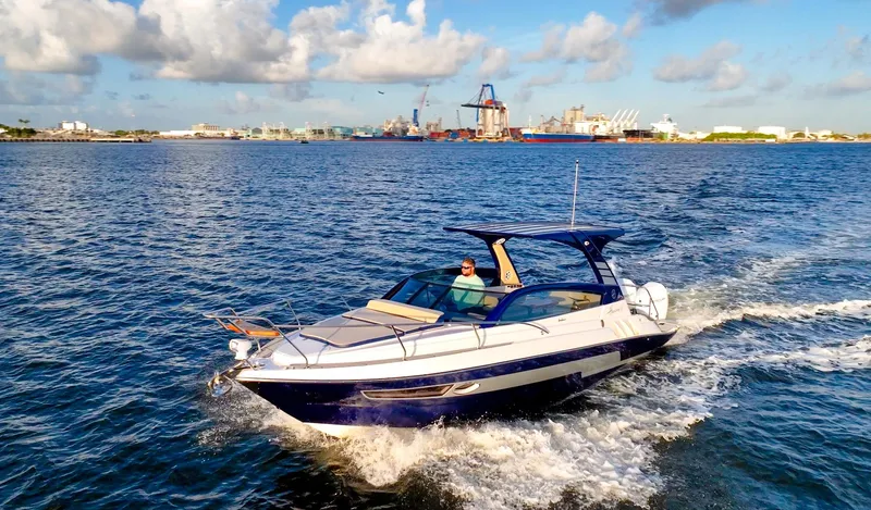  Yacht Photos Pics 2024 Hanover 305 boat cruising on a sunny day near an industrial port.