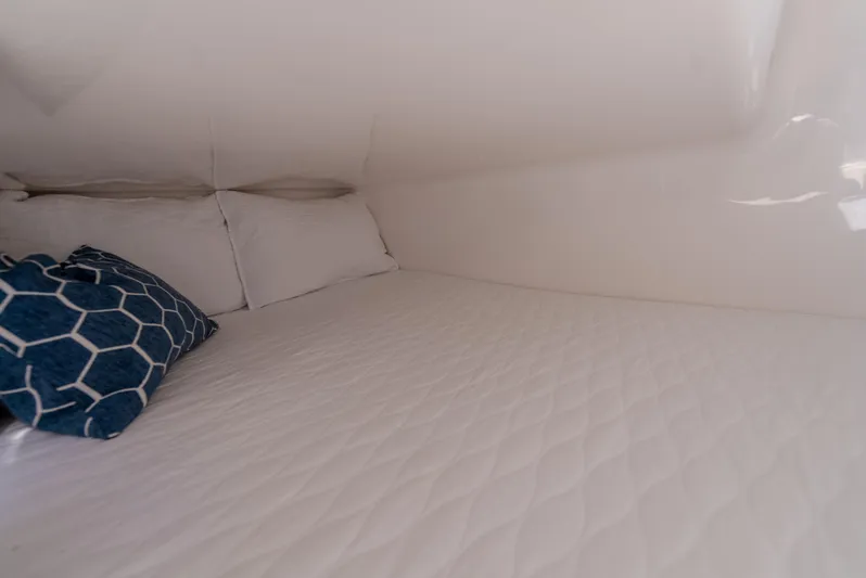  Yacht Photos Pics 2024 Hanover 305 interior cabin with white bedding and blue geometric pillow.