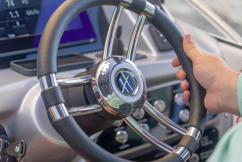  Yacht Photos Pics Steering wheel of a 2024 Hanover 305 boat, with a hand gripping it.