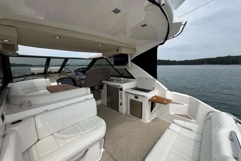 Absolutely Yacht Photos Pics Luxurious 2017 Regal 42 Sport Coupe yacht interior with white seating and kitchenette on a serene lake.