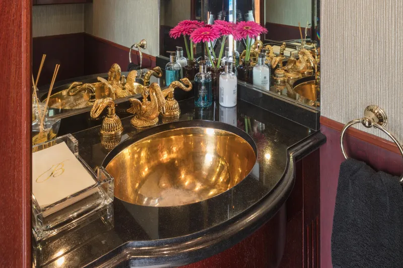 Blackwood Yacht Photos Pics Luxurious yacht bathroom with gold sink, ornate fixtures, and fresh flowers on a Broward 103, 1998.