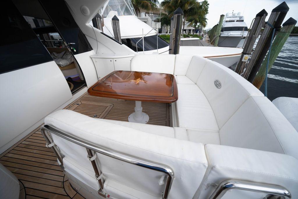 Luxurious 2007 Pershing 62' yacht with elegant white seating and wooden table on deck.