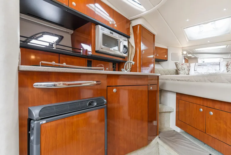Beau Dacious Yacht Photos Pics 2007 Sea Ray 310 Sundancer interior with kitchenette, featuring wood cabinetry and modern appliances.