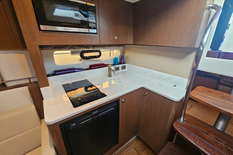 Levon II Yacht Photos Pics 2017 Sea Ray Sundancer 350 Coupe kitchen with microwave, stove, and wooden cabinetry.