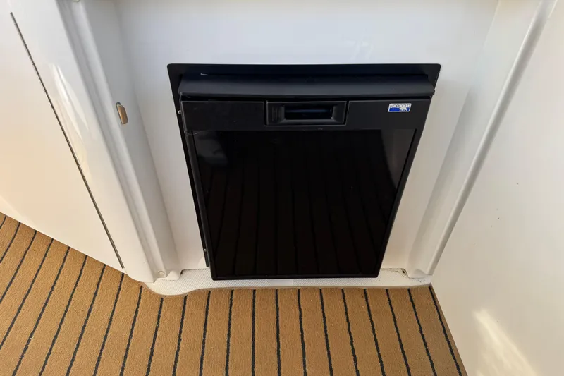  Yacht Photos Pics Black mini fridge on 2004 Sea Ray 390 Motor Yacht, set against striped flooring.
