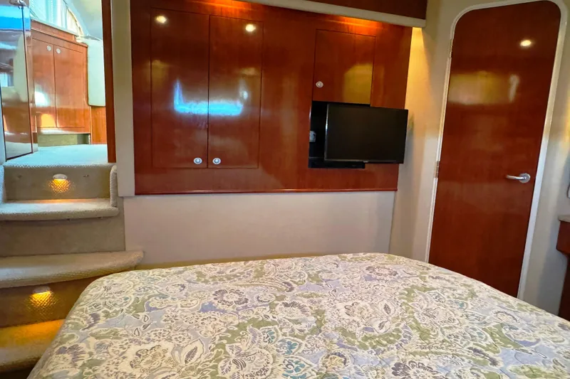 Yacht Photos Pics 2004 Sea Ray 390 Motor Yacht interior with wood cabinetry, TV, and patterned bedding.
