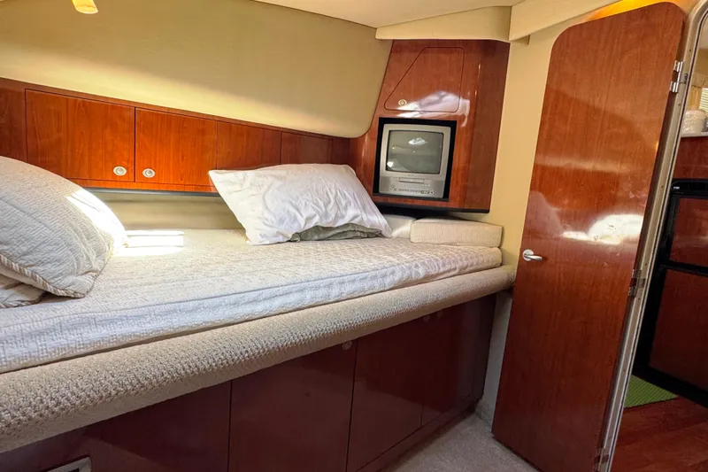 Yacht Photos Pics 2004 Sea Ray 390 Motor Yacht cabin with bed, TV, and wooden cabinetry.