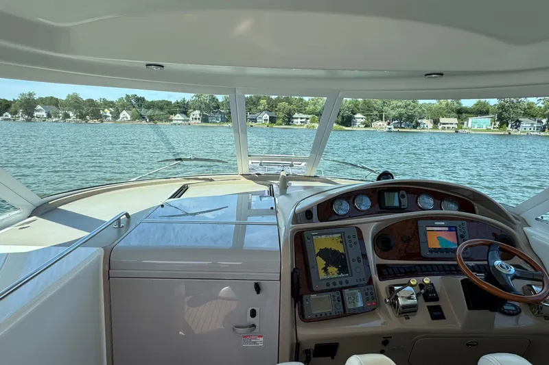  Yacht Photos Pics 2004 Sea Ray 390 Motor Yacht helm with navigation equipment, overlooking serene waterfront homes.