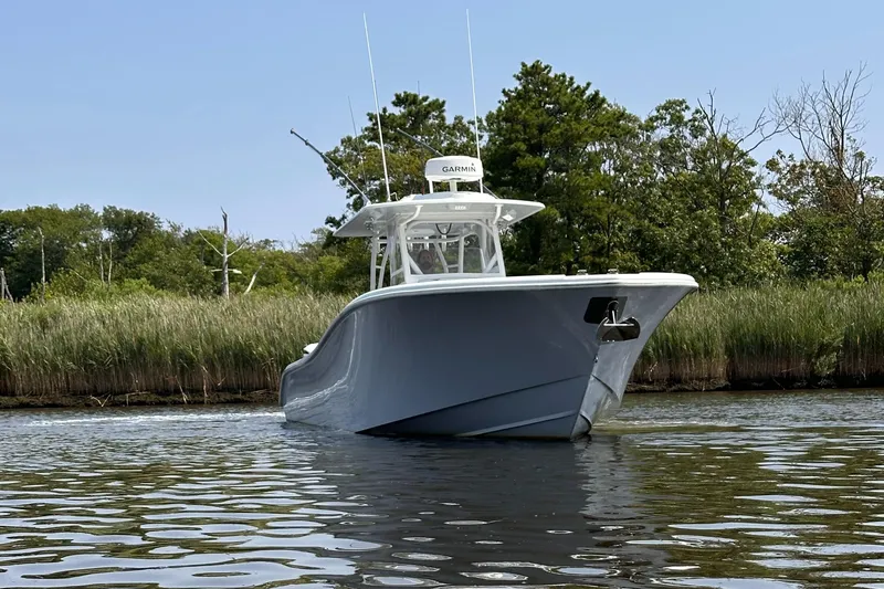  Yacht Photos Pics 2020 Yellowfin 36 boat on calm water, surrounded by lush greenery.