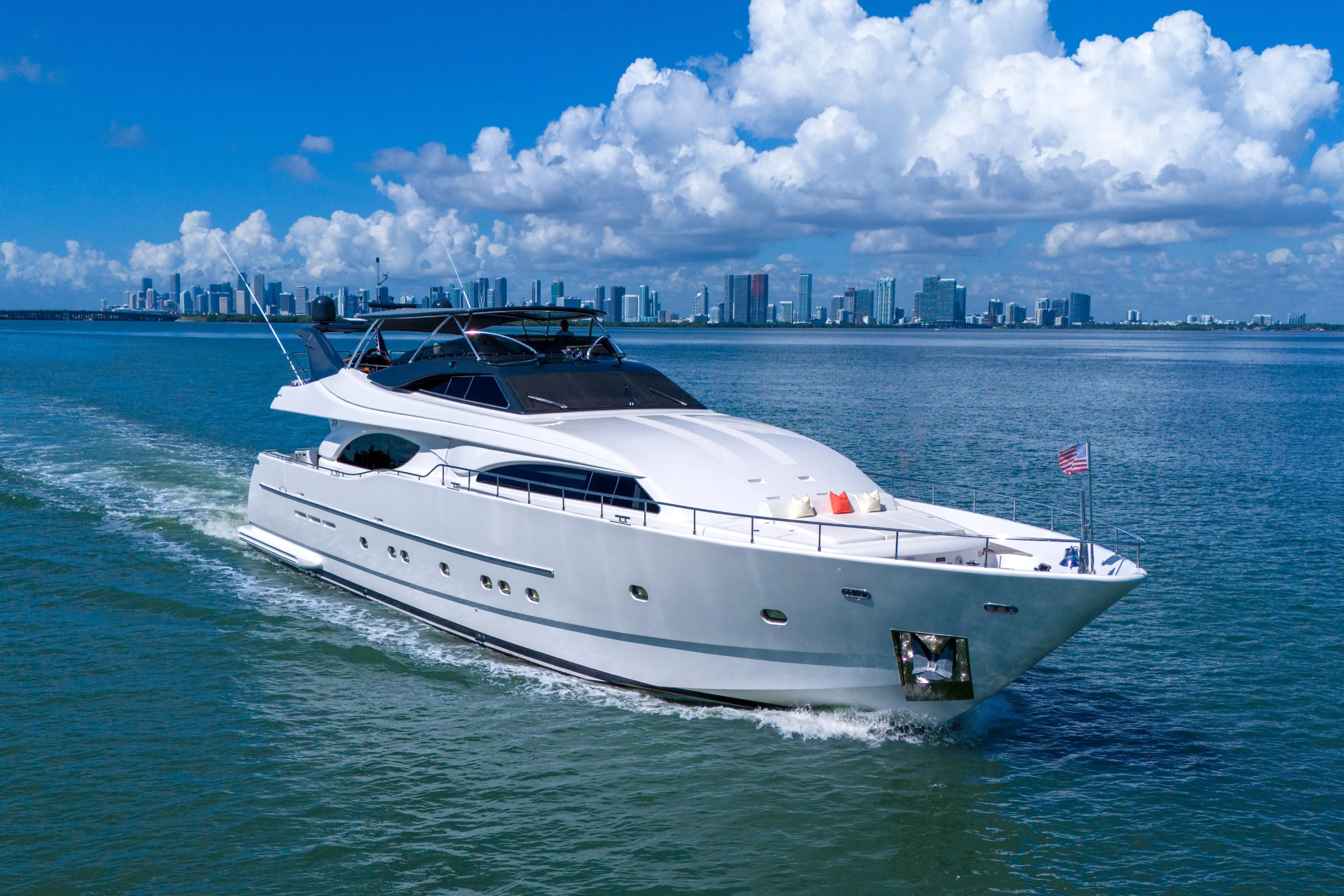 Sinpatico Yacht Photos Pics Luxurious 2002 Ferretti Yachts Custom Line 94 cruising near a city skyline under blue skies.