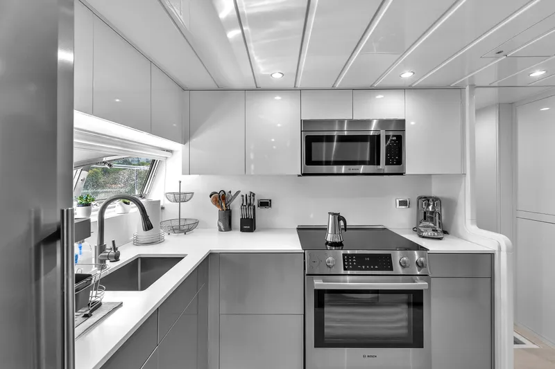 Sinpatico Yacht Photos Pics Modern kitchen in 2002 Ferretti Yachts Custom Line 94, featuring sleek appliances and white cabinetry.