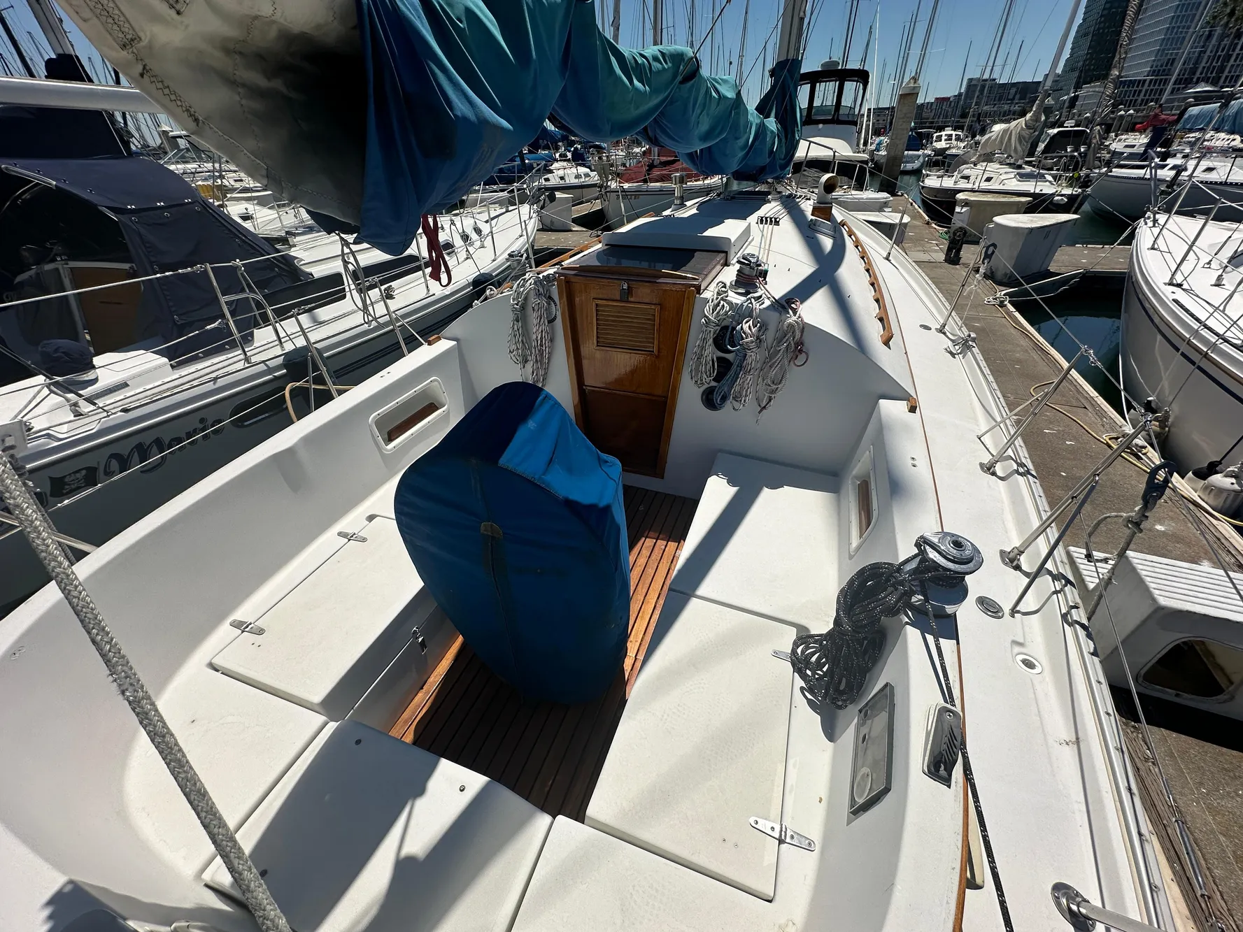 1986 Nonsuch Ultra sailboat cockpit in marina, featuring covered equipment and wooden accents.