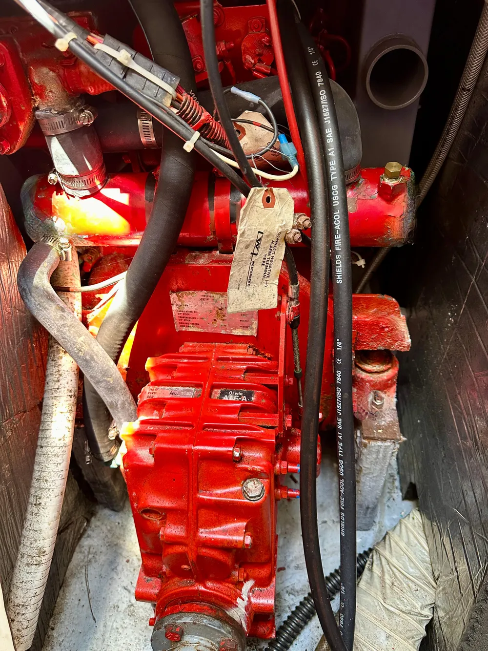 Red engine component of a 1986 Nonsuch Ultra boat, featuring various cables and hoses.