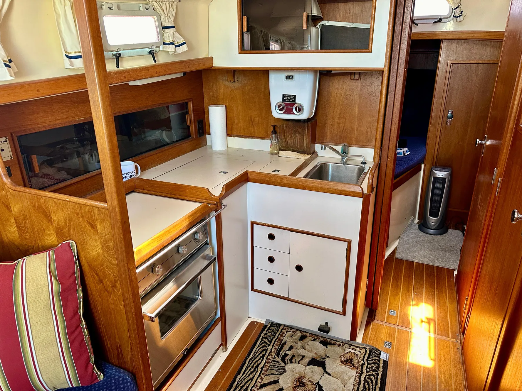 Compact kitchen in a 1986 Nonsuch Ultra sailboat with wood cabinetry and stainless steel appliances.