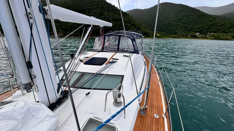 Cadence Yacht Photos Pics 2008 Jeanneau Sun Odyssey 54 DS yacht on serene water with lush hills in background.