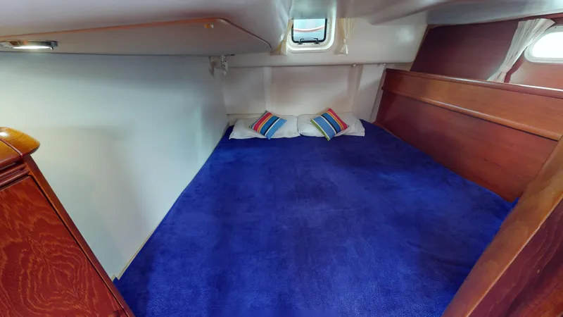 Cadence Yacht Photos Pics Cozy cabin interior of 2008 Jeanneau Sun Odyssey 54 DS with blue carpet and colorful pillows.