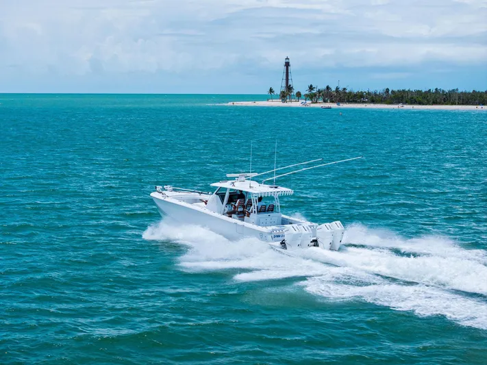 Down Range Yacht Photos Pics 2023 Barker Boatworks 40 HPC cruising near a lighthouse on turquoise waters.