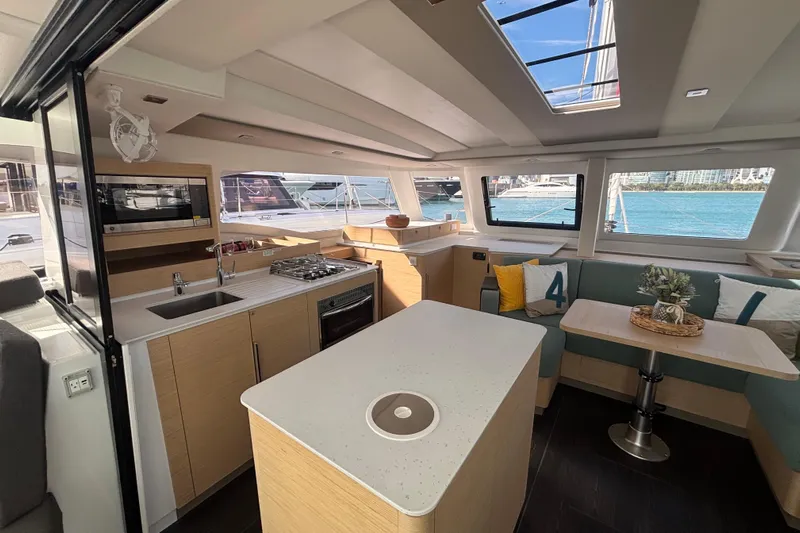 The Ilusion Yacht Photos Pics Luxurious interior of 2025 Fountaine Pajot 41 catamaran with modern kitchen and seating area.
