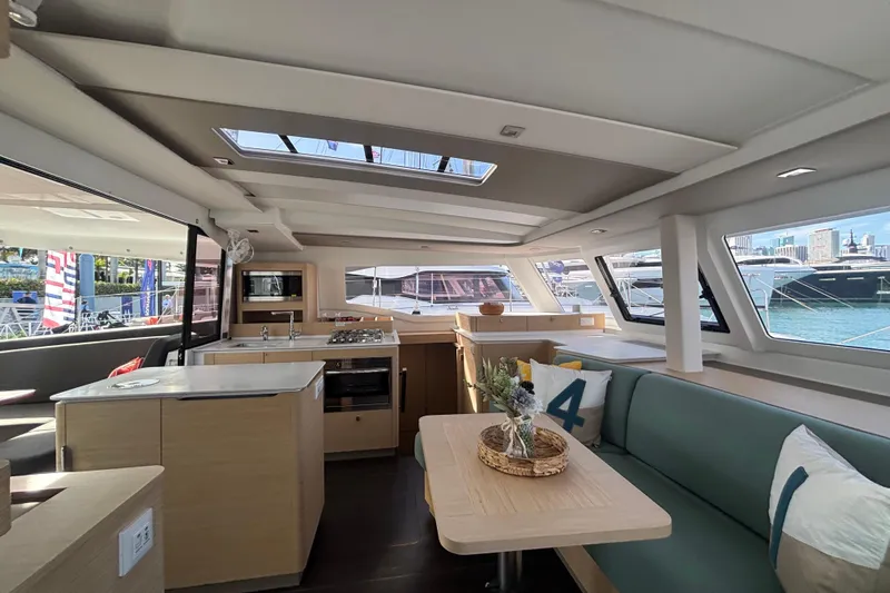 The Ilusion Yacht Photos Pics Luxurious interior of 2025 Fountaine Pajot 41 catamaran with modern kitchen and seating area.