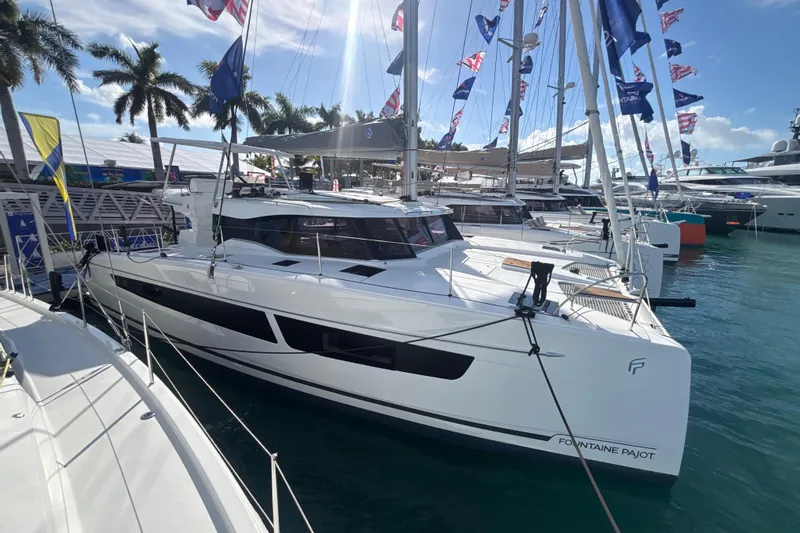 The Ilusion Yacht Photos Pics 2025 Fountaine Pajot 41 catamaran docked at a marina with flags and palm trees.