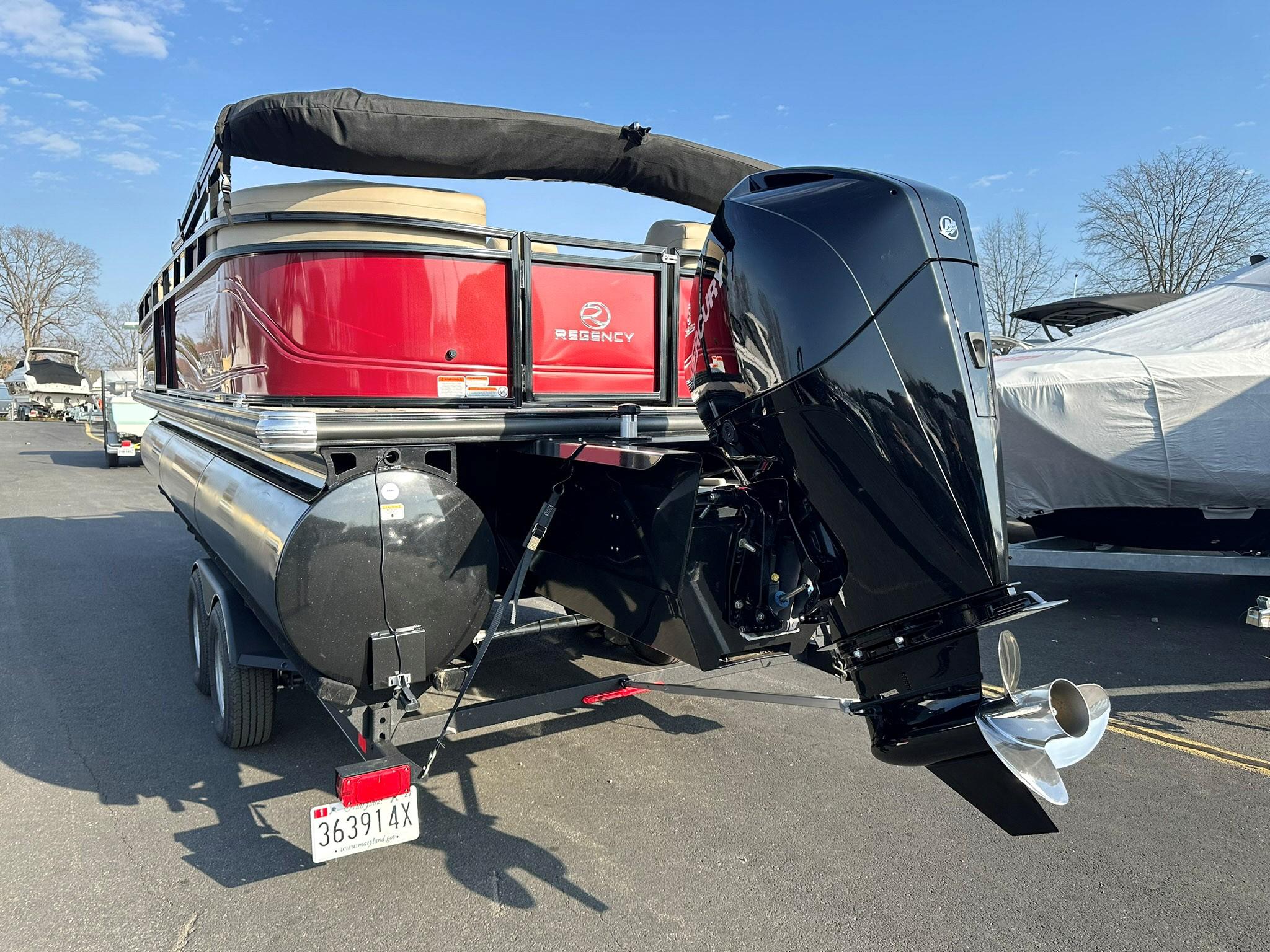 2023 Regency 230 DL3 pontoon boat with powerful outboard motor, parked on trailer.