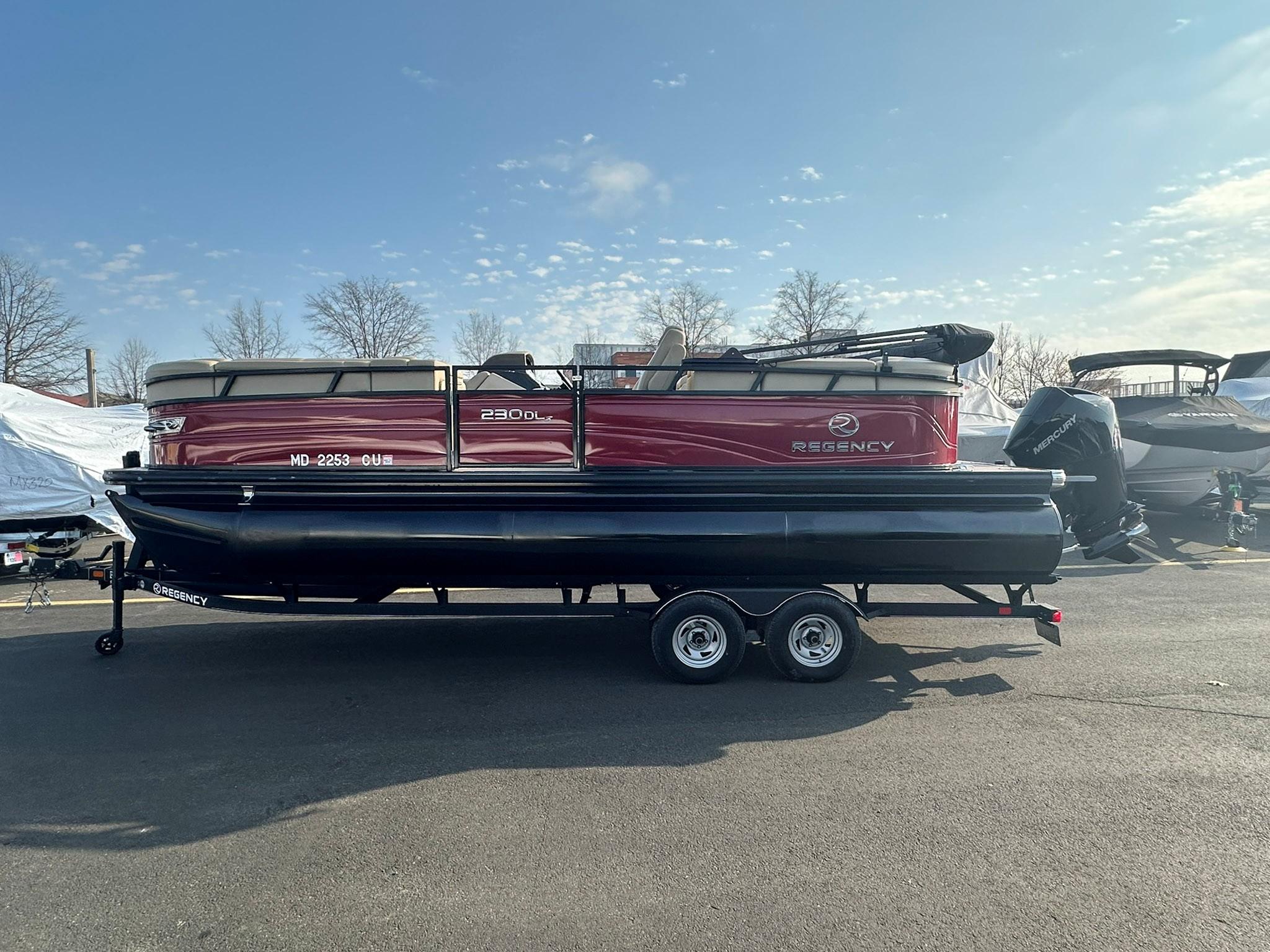 2023 Regency 230 DL3 pontoon boat on trailer, parked outdoors under clear sky.
