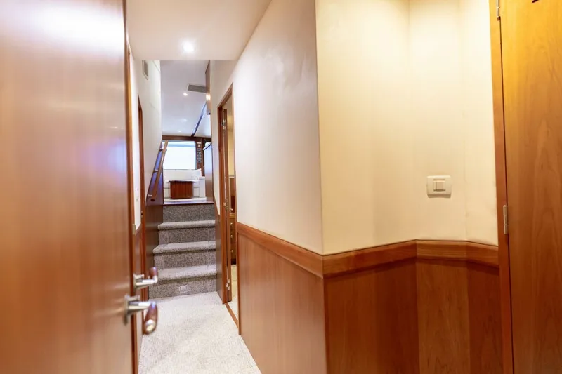  Yacht Photos Pics Hallway inside 2012 Hatteras 60 GT yacht, featuring wooden paneling and carpeted stairs.