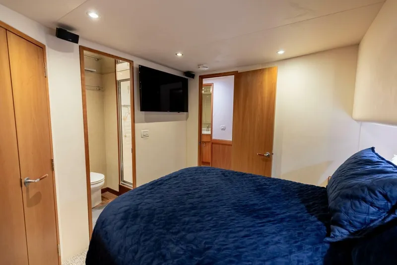  Yacht Photos Pics Bedroom interior of 2012 Hatteras 60 GT yacht with blue bedding and ensuite bathroom.