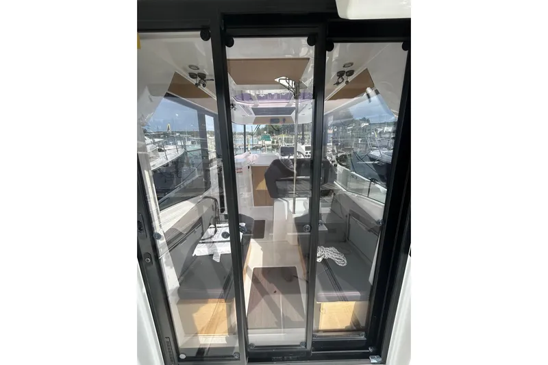  Yacht Photos Pics 2020 Beneteau Barracuda 9 interior view through glass doors, showcasing seating and helm.