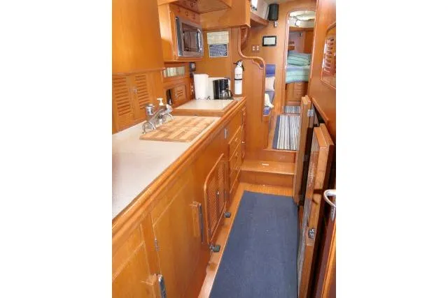 Sun Bird Yacht Photos Pics 2002 Tayana 460 Vancouver Pilothouse interior galley with wood cabinetry and modern appliances.