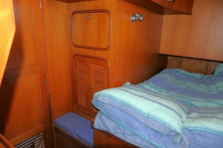 Sun Bird Yacht Photos Pics Cozy cabin interior of 2002 Tayana 460 Vancouver Pilothouse with wooden cabinetry and bedding.