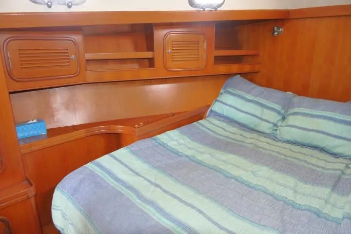 Sun Bird Yacht Photos Pics Cozy bedroom in 2002 Tayana 460 Vancouver Pilothouse with wooden cabinetry and striped bedding.