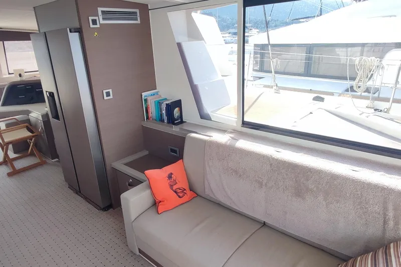 Helios Yacht Photos Pics Luxurious interior of 2021 Bali 5.4 yacht with sofa, books, and large window view.