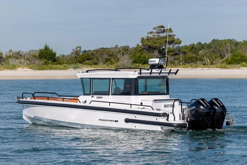  Yacht Photos Pics 2024 Axopar 28 CABIN boat cruising on water near a sandy shoreline.