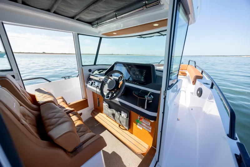  Yacht Photos Pics 2024 Axopar 28 CABIN interior with modern dashboard and leather seating on calm water.