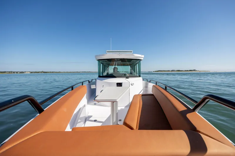  Yacht Photos Pics 2024 Axopar 28 CABIN boat on calm water, featuring sleek design and comfortable seating.